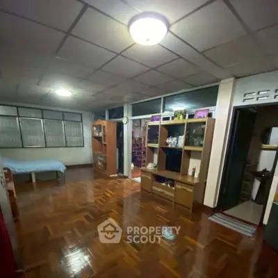 Spacious living area with wooden flooring and modern shelving units.