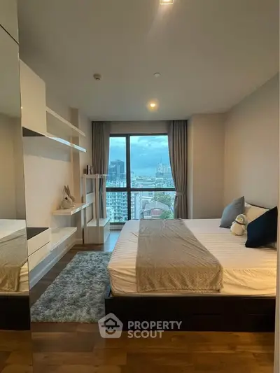 Modern bedroom with city view, featuring cozy decor and large window for natural light.