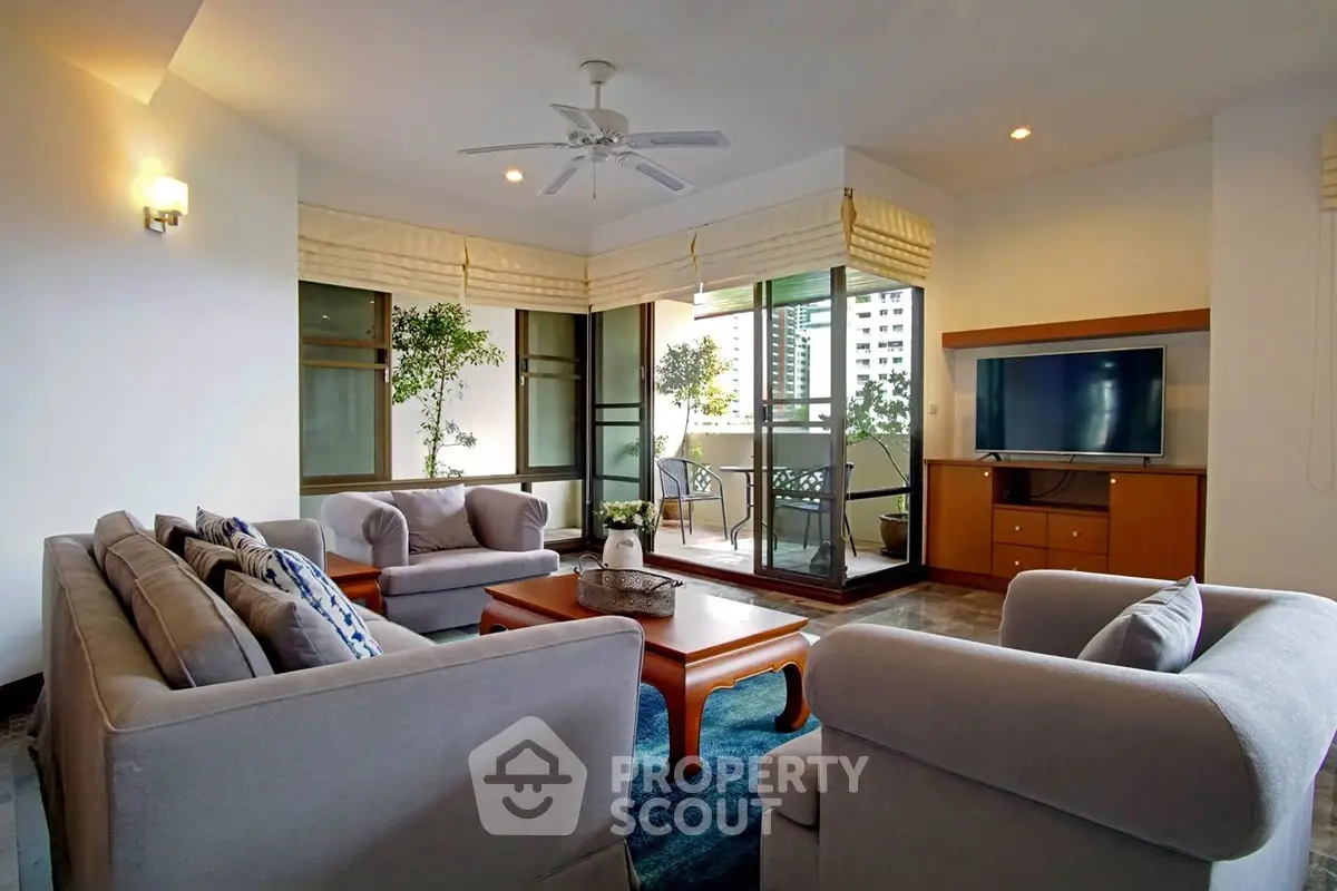 Spacious living room with modern furniture and large windows opening to a balcony with city views.