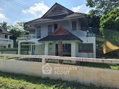 Charming two-story house with a tiled roof and spacious front yard, perfect for family living.