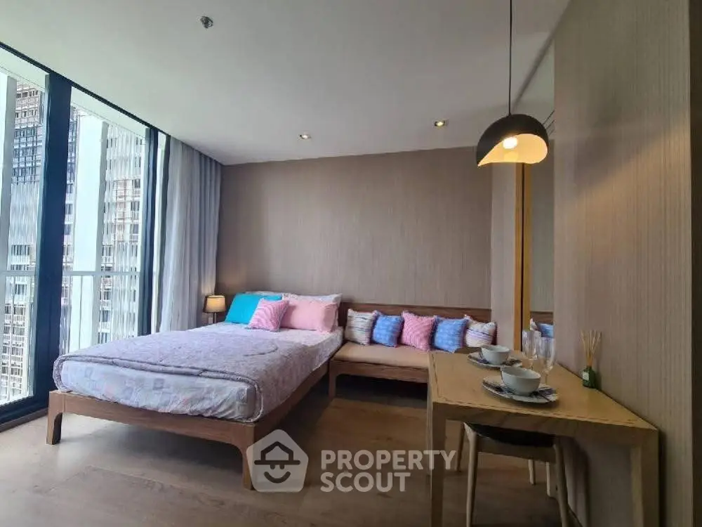 Modern bedroom with large windows and cozy dining area in urban apartment