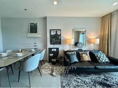 Modern living room with stylish decor and dining area, featuring a sleek black sofa and elegant dining set.