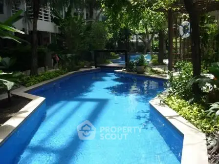 Luxurious outdoor pool surrounded by lush greenery in a modern residential complex.