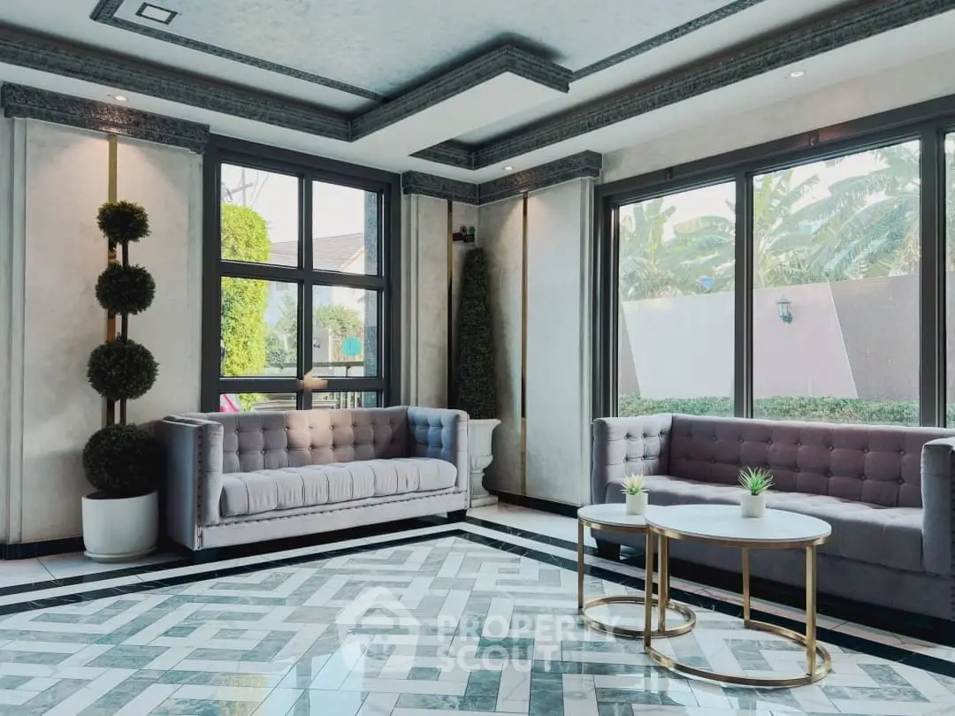 Elegant living room with modern sofas and large windows overlooking lush greenery.