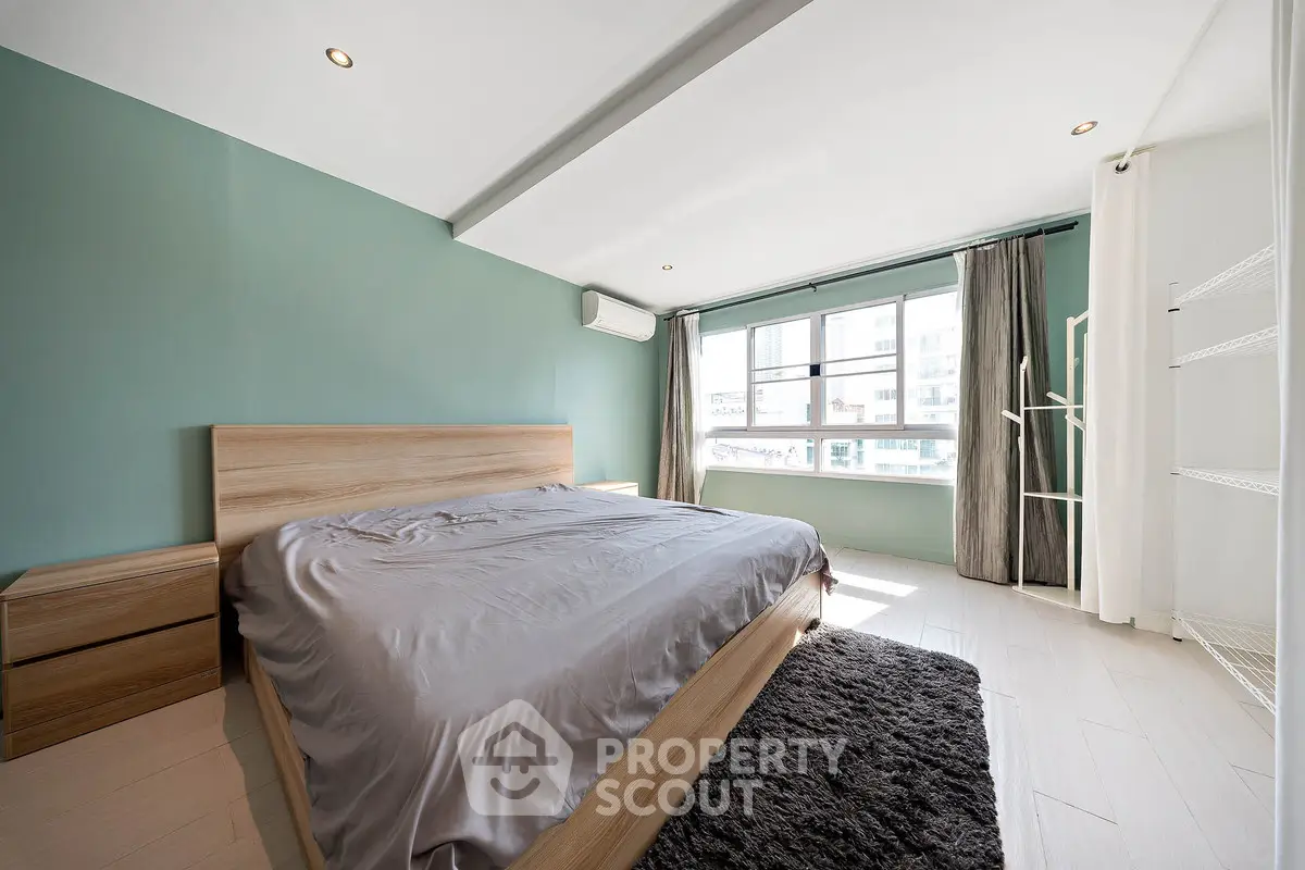 Spacious bedroom with modern design, featuring a large window and stylish decor, perfect for comfortable living.