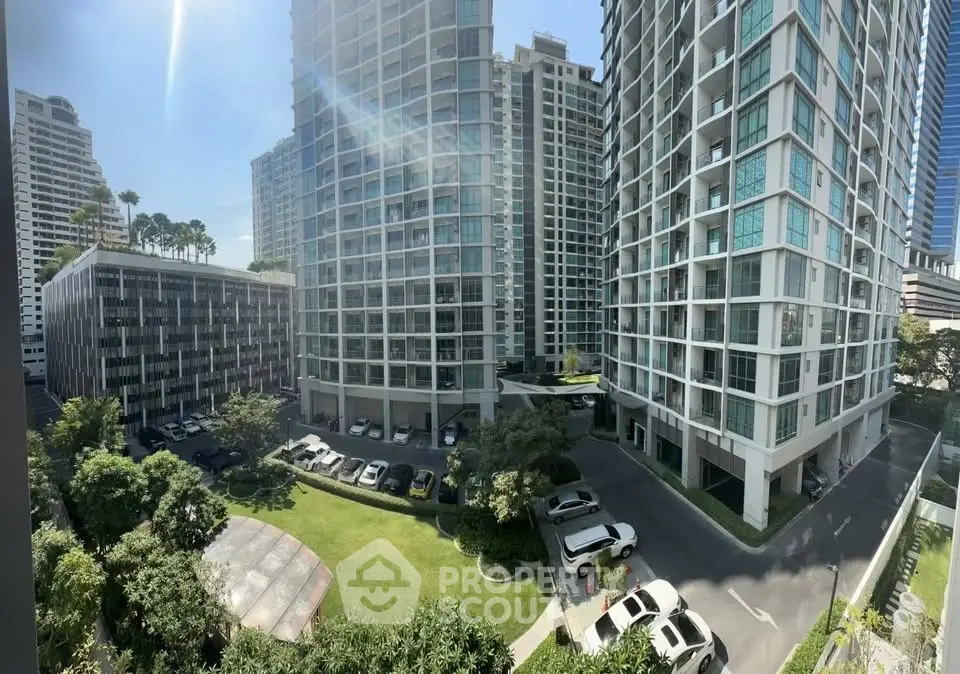 Panoramic view of modern high-rise residential buildings with lush green garden and parking area.