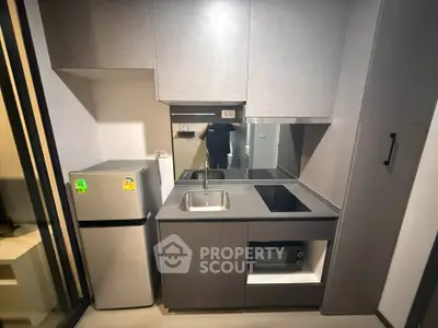 Modern compact kitchen with sleek cabinetry and built-in appliances in a stylish apartment.