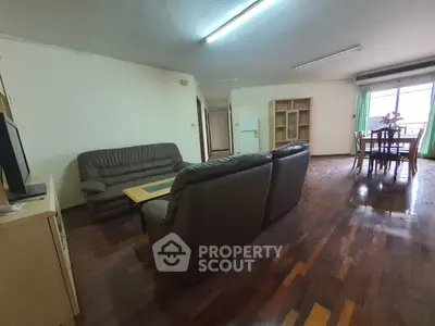 Spacious living room with leather sofas and dining area, featuring wooden flooring and natural light.