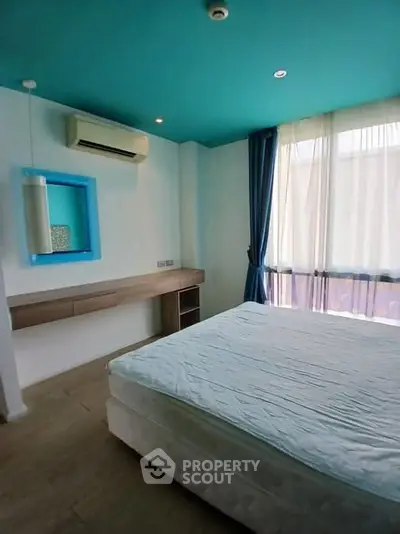 Modern bedroom with teal ceiling and large windows for natural light.