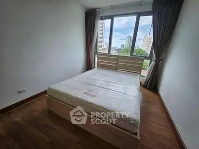 Spacious bedroom with large window offering city views and natural light.