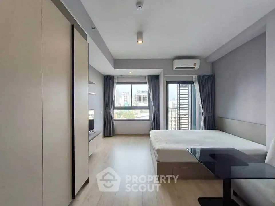 Modern bedroom with city view, featuring sleek furniture and natural light.