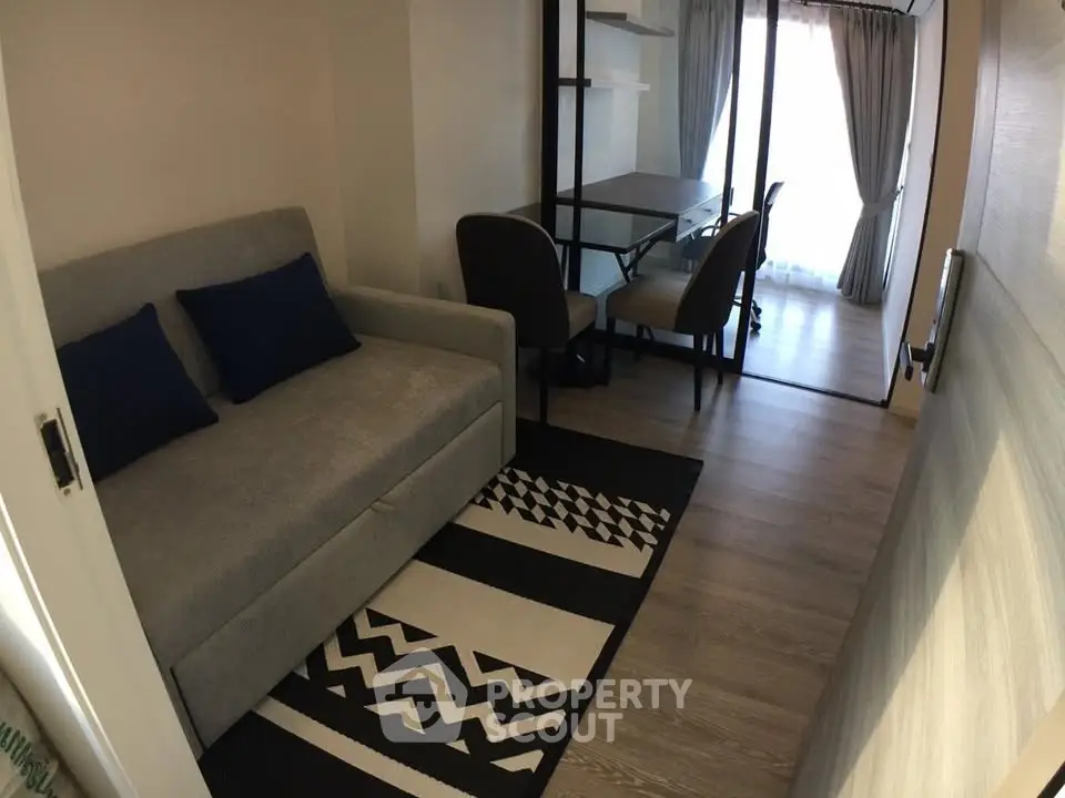 Modern living room with stylish decor and natural light, featuring a cozy sofa and work desk.