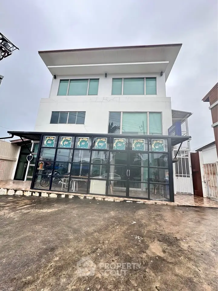 Modern three-story commercial building with large glass facade and spacious parking area.