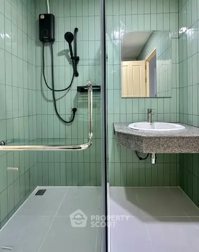 Modern bathroom with sleek green tiles and glass shower enclosure