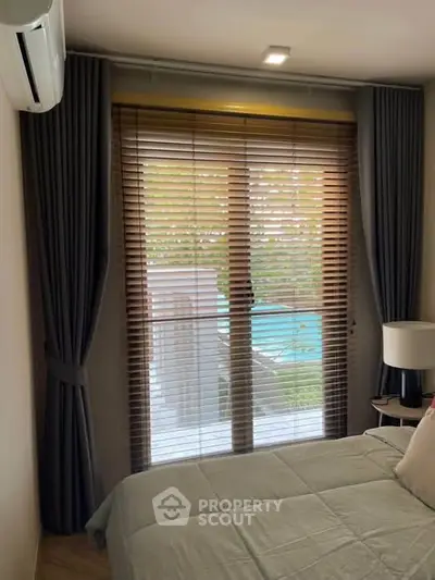 Cozy bedroom with pool view through large window and elegant curtains.