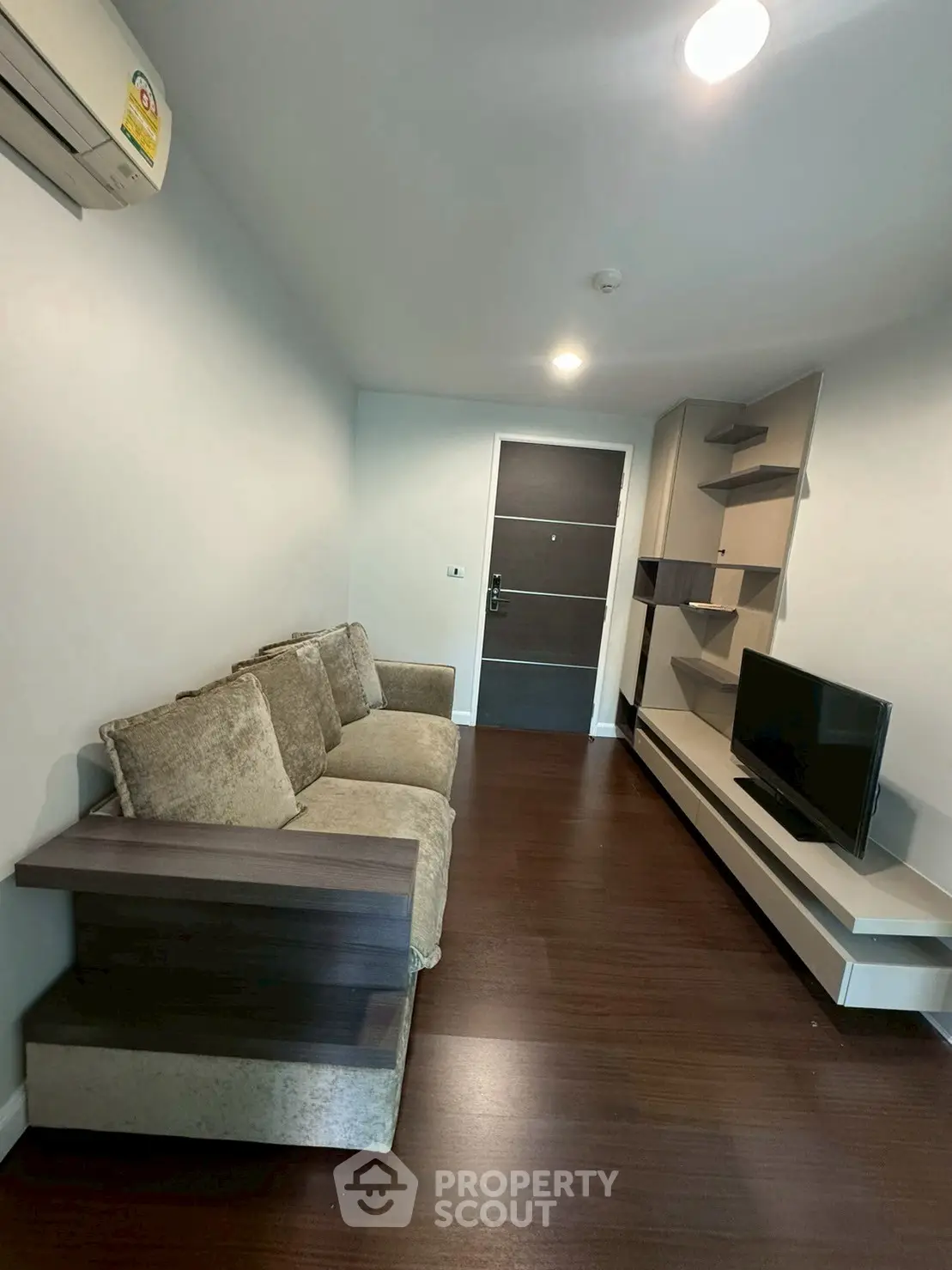 Modern living room with sleek furniture and wall-mounted TV in a cozy apartment.