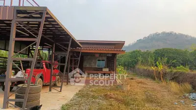 Charming rural property with a rustic exterior and scenic mountain backdrop, featuring a spacious carport and lush greenery.
