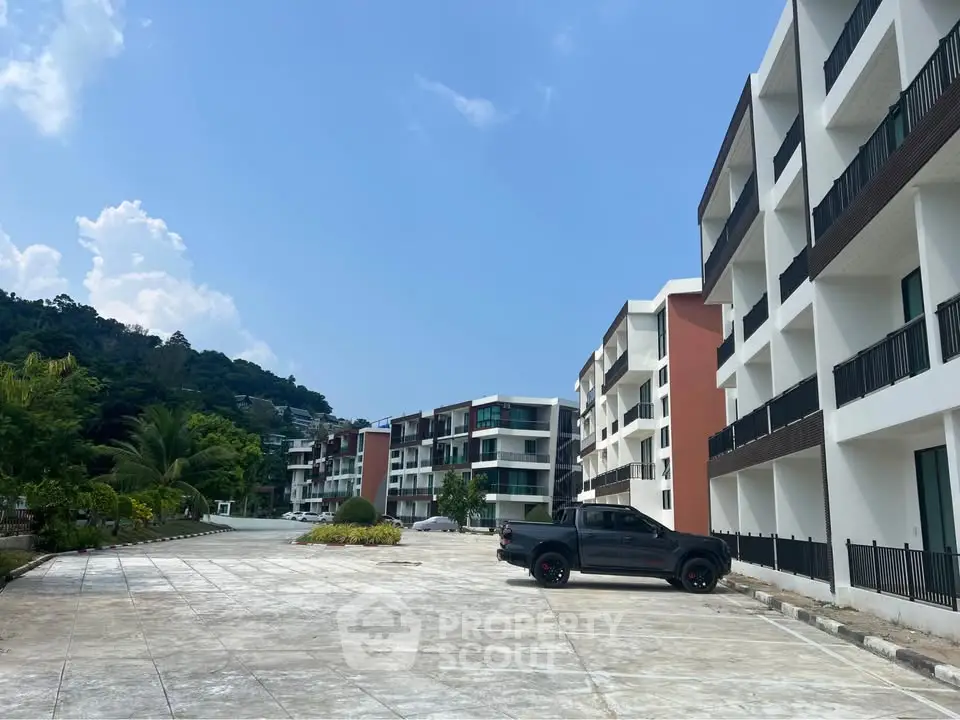 Modern apartment complex with spacious parking and scenic mountain backdrop.