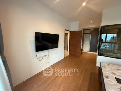 Modern living room with wall-mounted TV and wooden flooring in a stylish apartment.