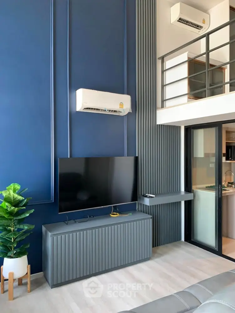 Modern living room with high ceiling and mezzanine, featuring sleek TV setup and stylish decor.