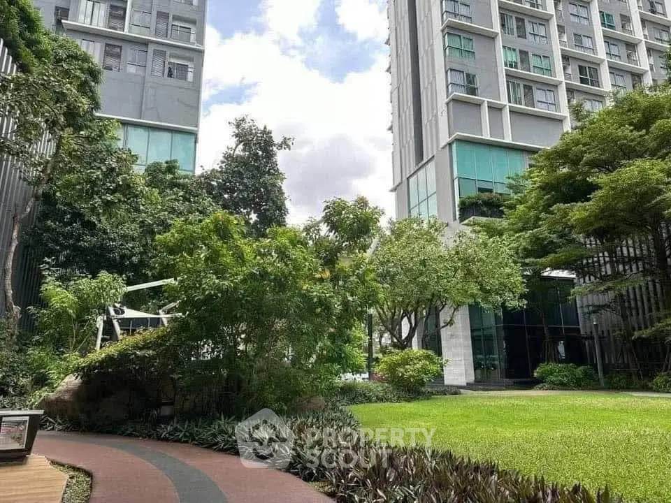 Luxurious modern apartment complex with lush green garden and tall buildings.