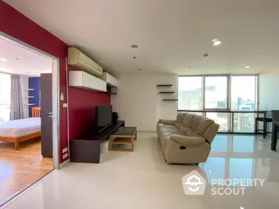 Spacious open-plan living area with glossy tiled floors, modern furniture, and abundant natural light leading to a cozy bedroom and balcony with city views.