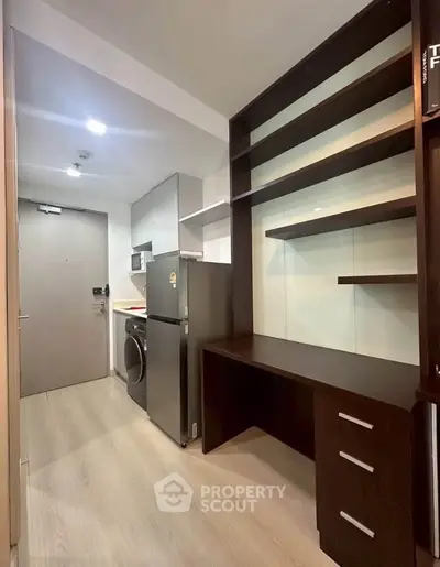 Modern compact kitchen with fridge, washing machine, and built-in shelves in a stylish apartment.