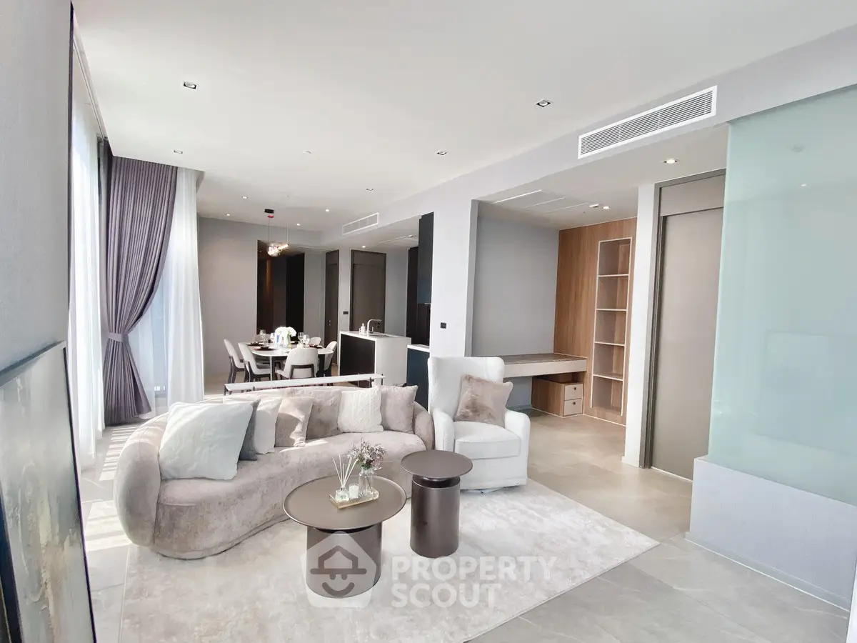 Luxurious modern living room with elegant decor and open dining area, featuring plush seating and ambient lighting.