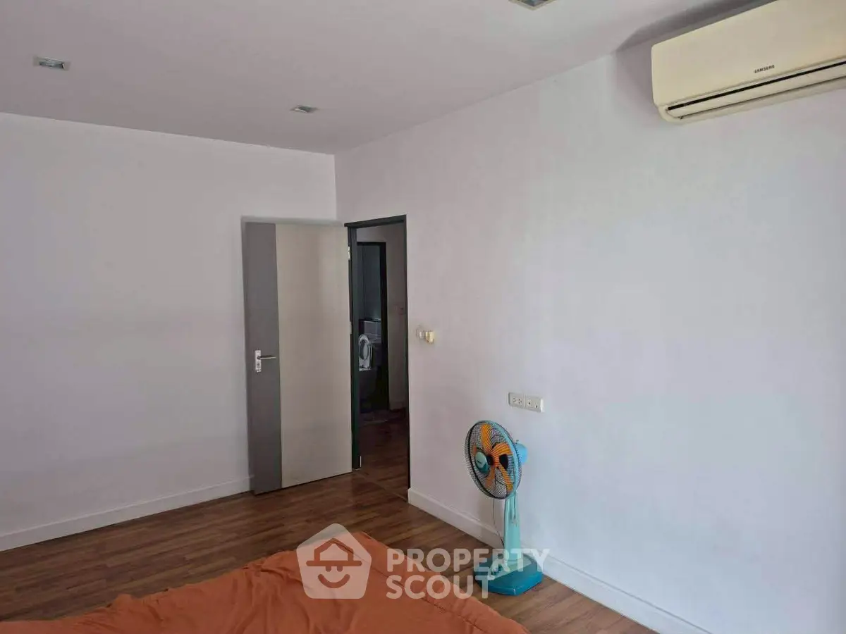Spacious bedroom with air conditioning and wooden flooring, ideal for comfort and relaxation.