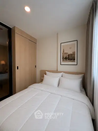 Cozy bedroom with modern decor and ample natural light, featuring a comfortable bed and stylish artwork.