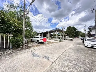 Charming suburban street view with residential homes and parked cars under a cloudy sky.
