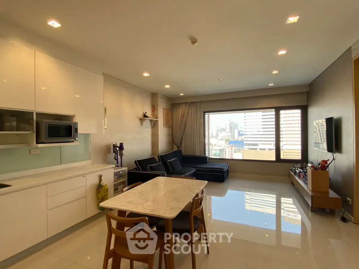 Modern open-layout living room with city view, sleek kitchen, and stylish furnishings.