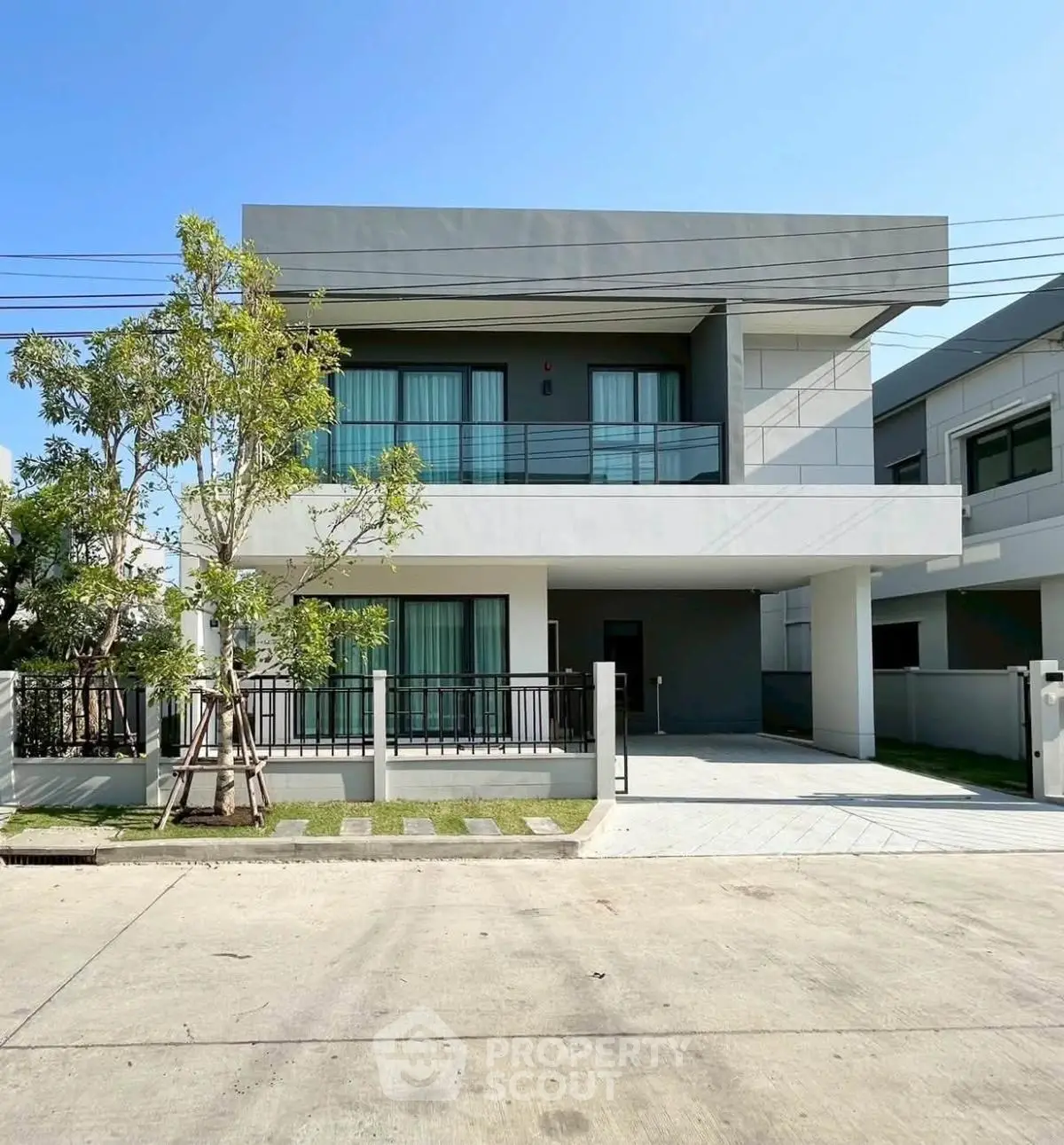 Modern two-story house with sleek design and spacious driveway in a suburban neighborhood.