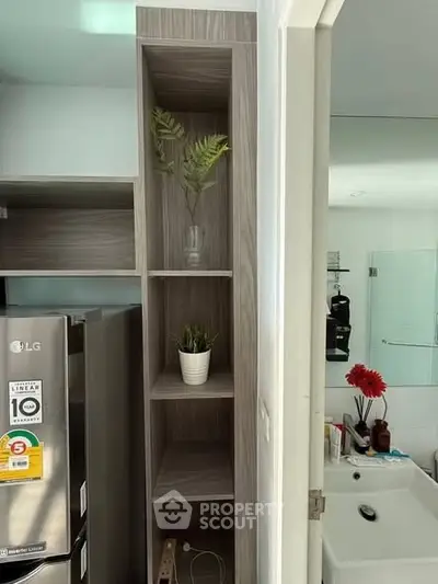 Modern kitchen with sleek shelving and stainless steel fridge, adjacent to a stylish bathroom.
