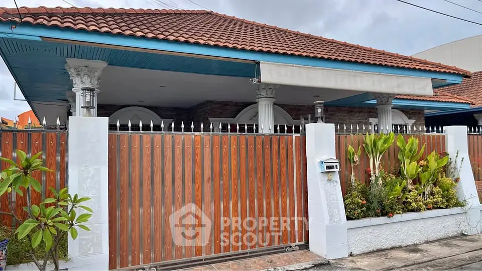 Charming single-story home with red tile roof and lush garden, featuring a secure wooden fence and inviting entrance.