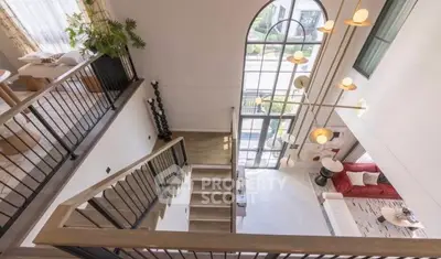 Stunning open-concept living space with high ceilings and elegant staircase