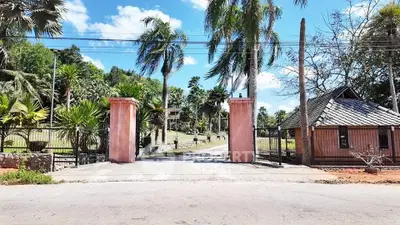 Charming gated entrance with lush greenery and palm trees, offering a serene and inviting atmosphere.