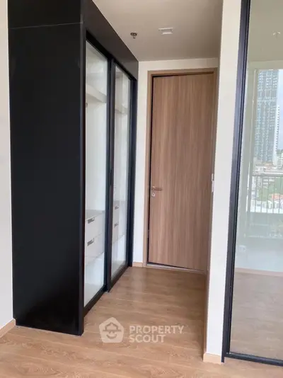 Modern apartment interior with sleek wooden flooring and glass wardrobe doors