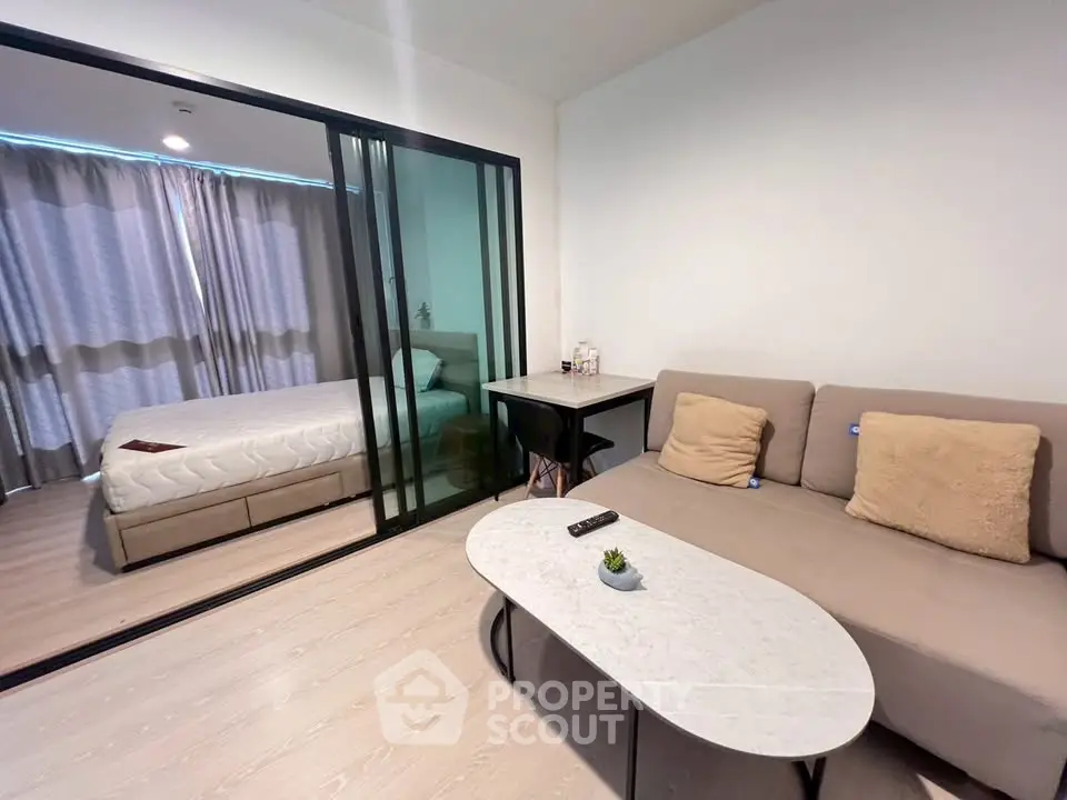 Modern studio apartment with cozy living area and bedroom separated by glass partition.