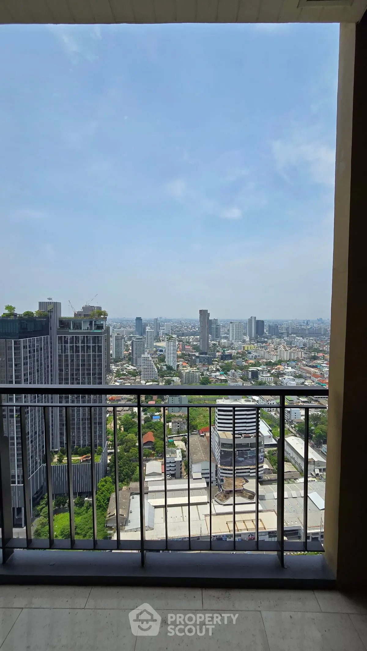 Stunning high-rise balcony view overlooking city skyline and lush greenery.