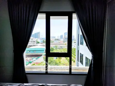 Spacious bedroom with large window offering stunning cityscape views, perfect for urban living.