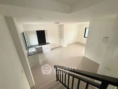 Spacious open-plan living area with modern kitchen and sleek staircase, perfect for contemporary living.