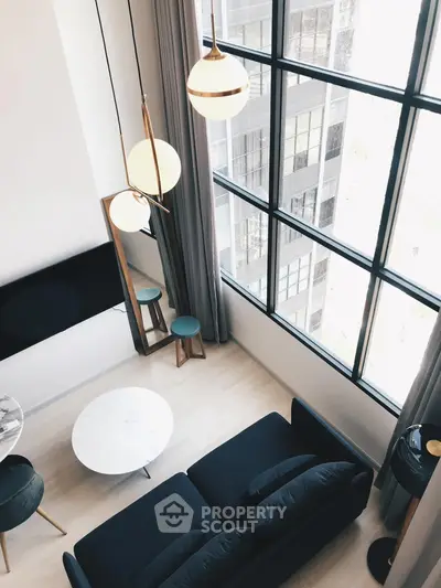 Modern living room with high ceilings and large windows offering city views.