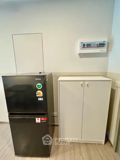 Modern kitchen corner with sleek black fridge and white storage cabinet
