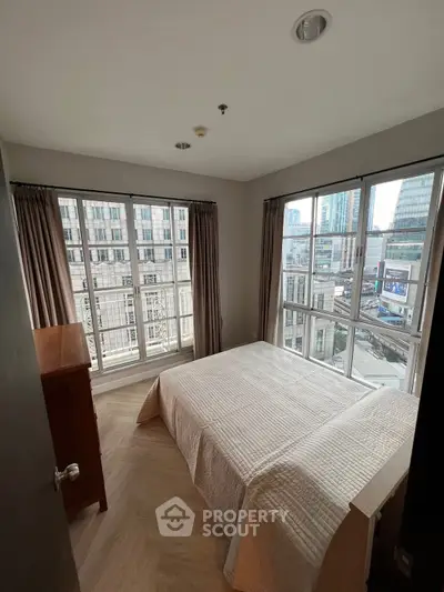 Bright bedroom with large windows offering stunning city views in modern apartment.