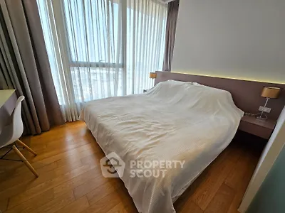 Modern bedroom with large window and elegant decor in a high-rise apartment.