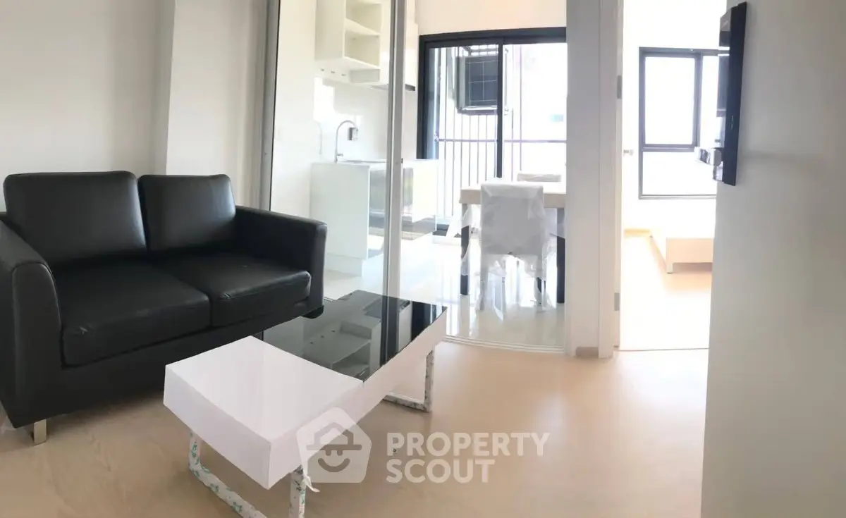 Modern living room with sleek black sofa and glass coffee table in bright apartment