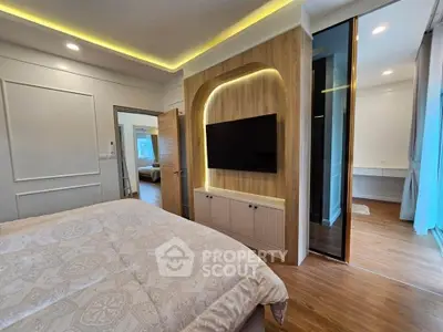 Luxurious bedroom with modern design and ambient lighting, featuring a wall-mounted TV and elegant decor.