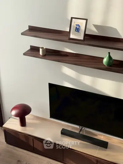 Modern living room with stylish shelves, TV, and elegant decor accents.