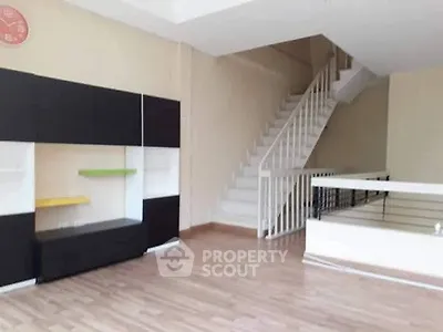Spacious modern living room with sleek staircase and stylish shelving unit.